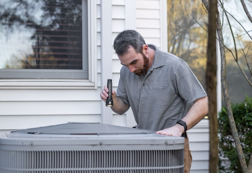 HVAC technician checking an outdoor AC condenser