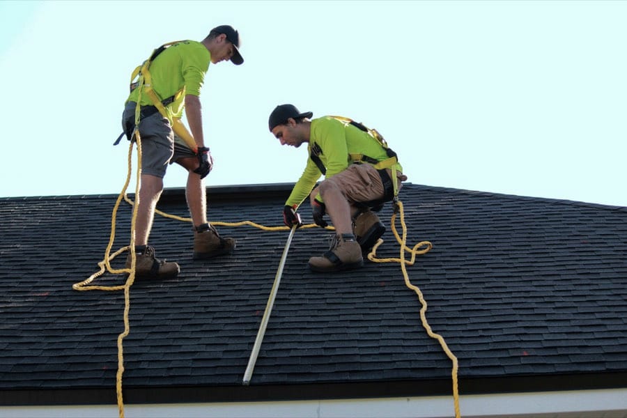 Two roofers working on an asphalt shingle roof
